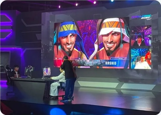 The Gamers8 broadcast desk in front of the arena mural